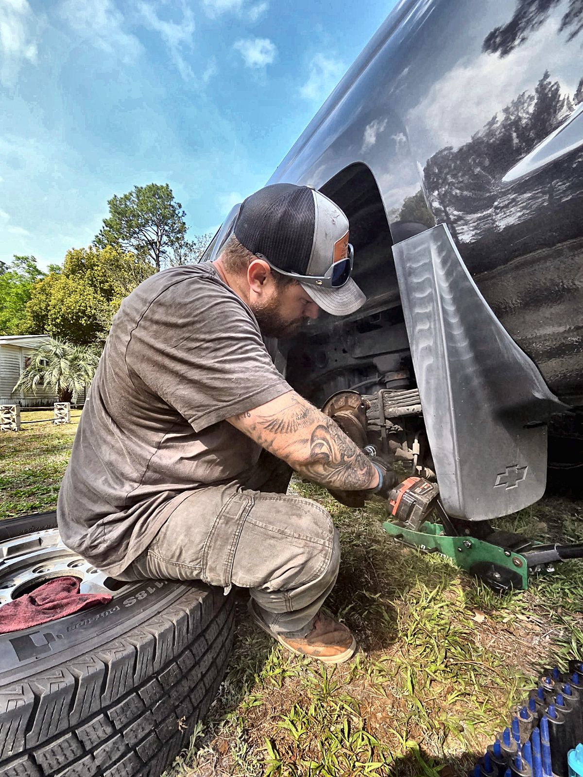 C&C mechanic replacing a wheel hub on a lifted Chevy truck on-site